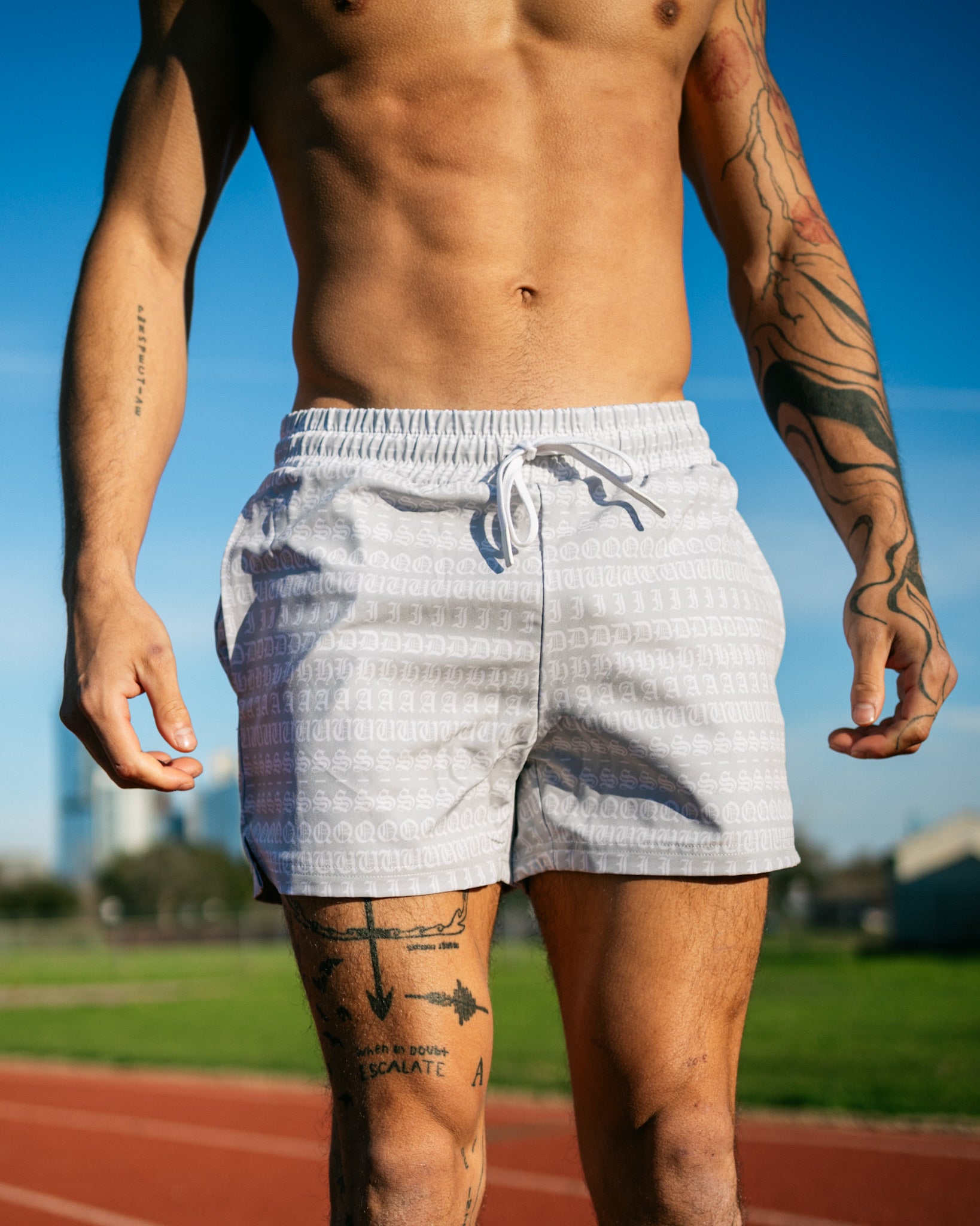 A runner preparing for a run around the track while wearing a pair of SquidHaus' men's 4 inch inseam mesh shorts in white