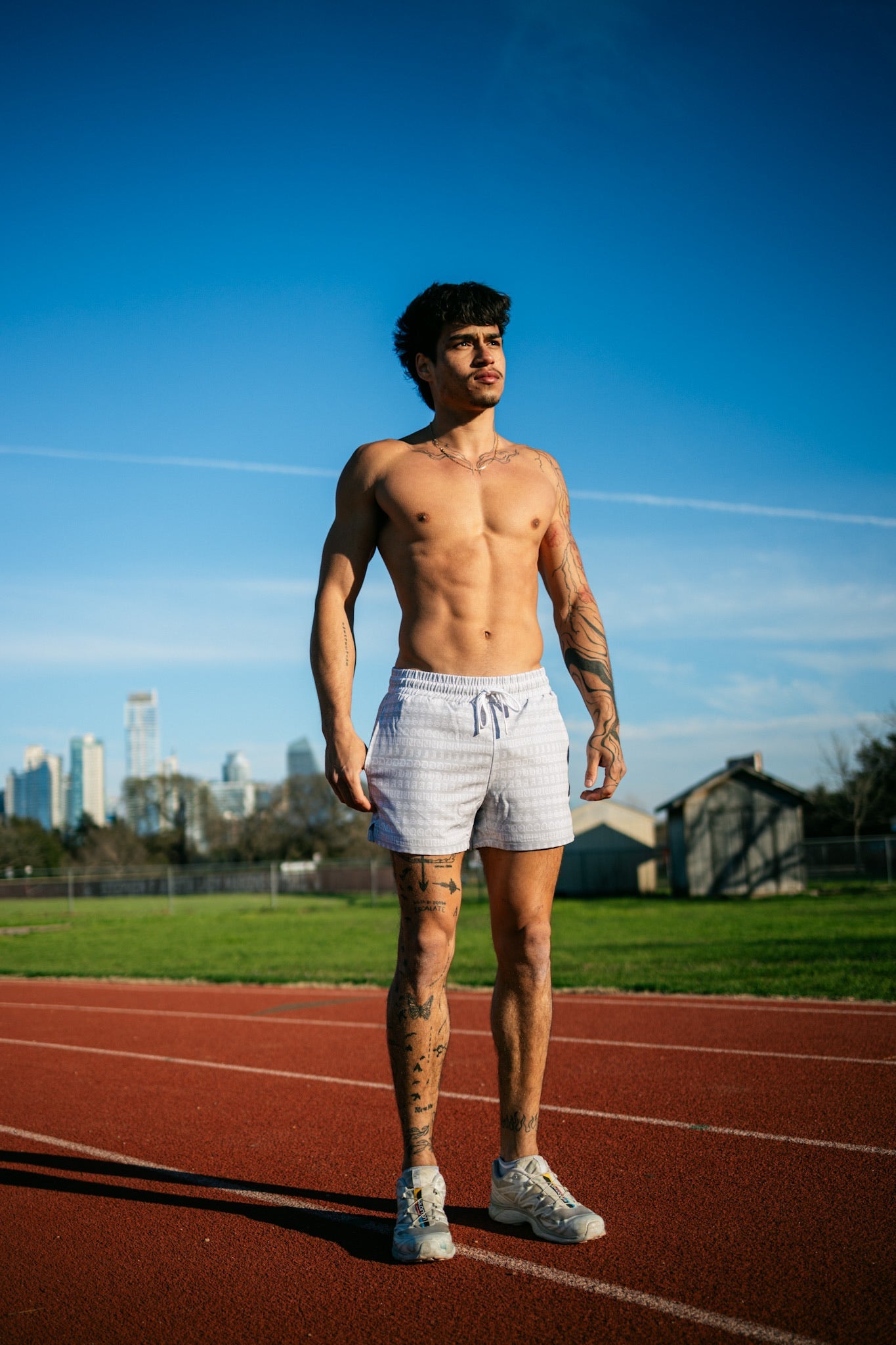 A runner preparing to run around the track while wearing a pair of SquidHaus' men's 4 inch inseam mesh shorts in white