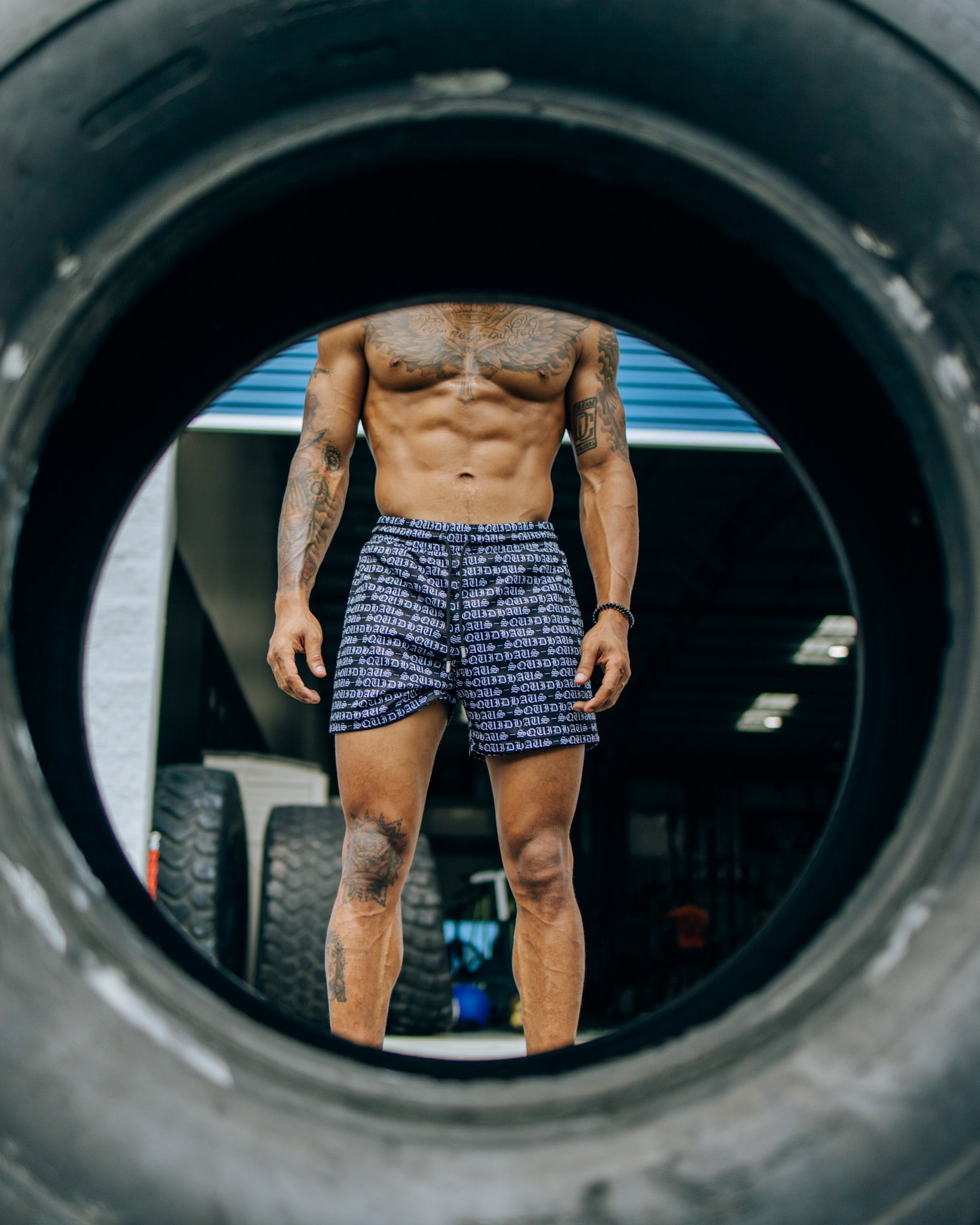 An athlete seen through the whole of a workout tire, wearing 4 inch inseam mesh shorts in black from SquidHaus