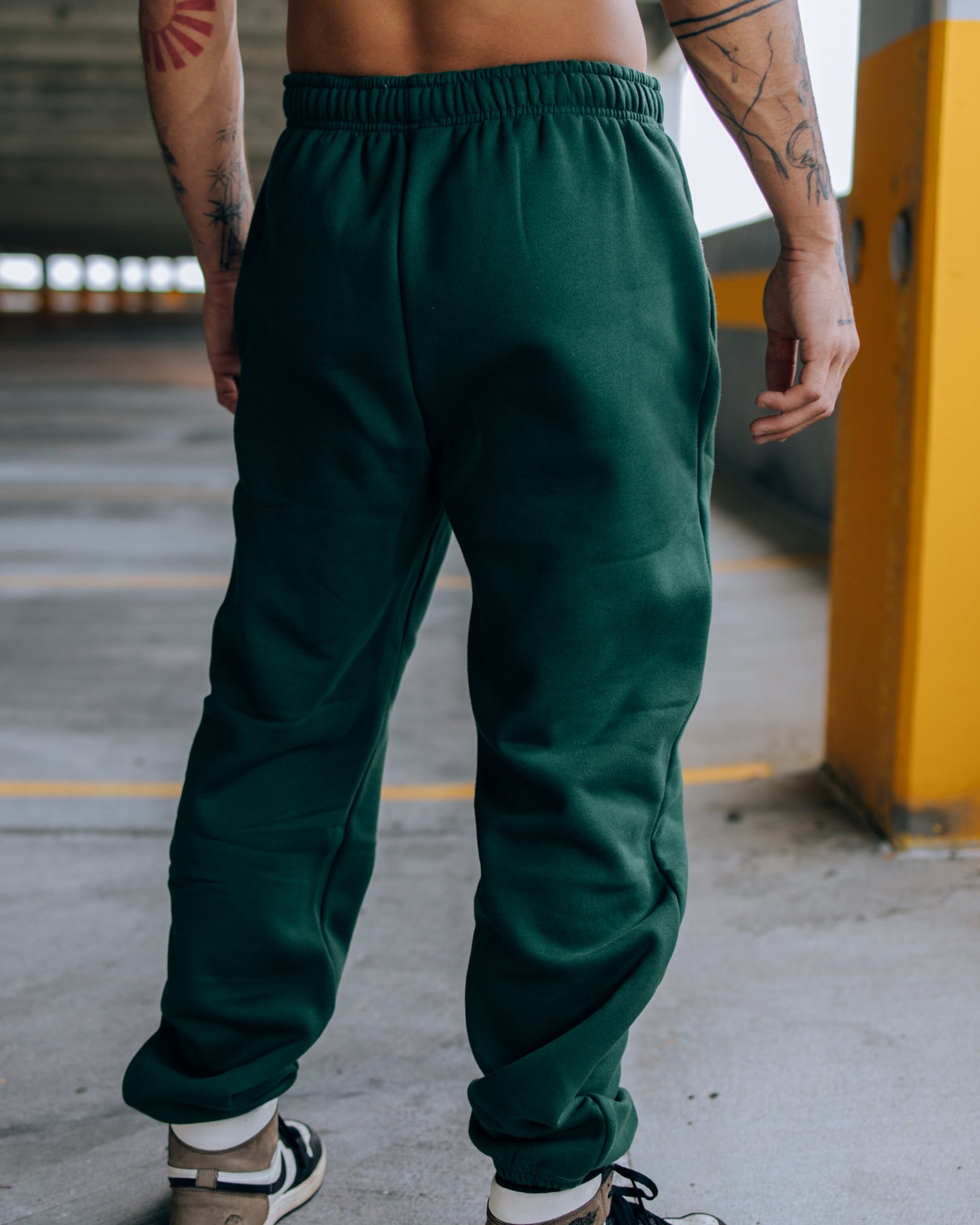 A rear view of a man wheraing SquidHaus Death Over Average sweatpants in green