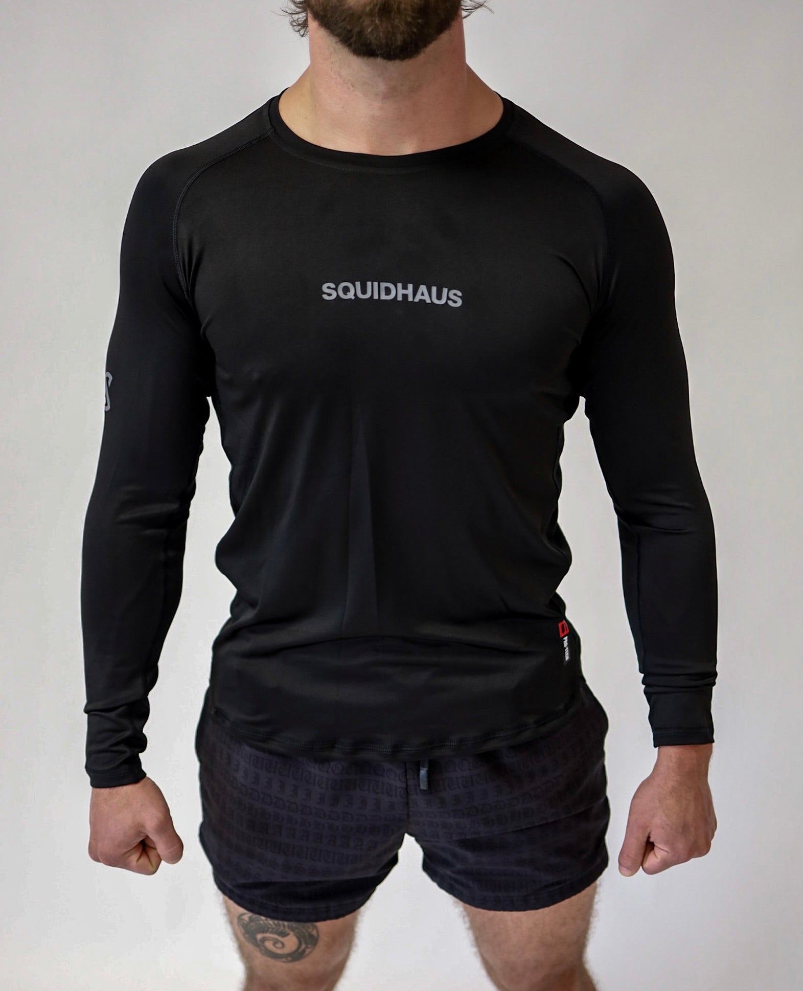 An athlete wearing a Pro-Tech V1 athletic-fitted long sleeve t-shirt and 4" inseam mesh shorts in black, both from SquidHaus