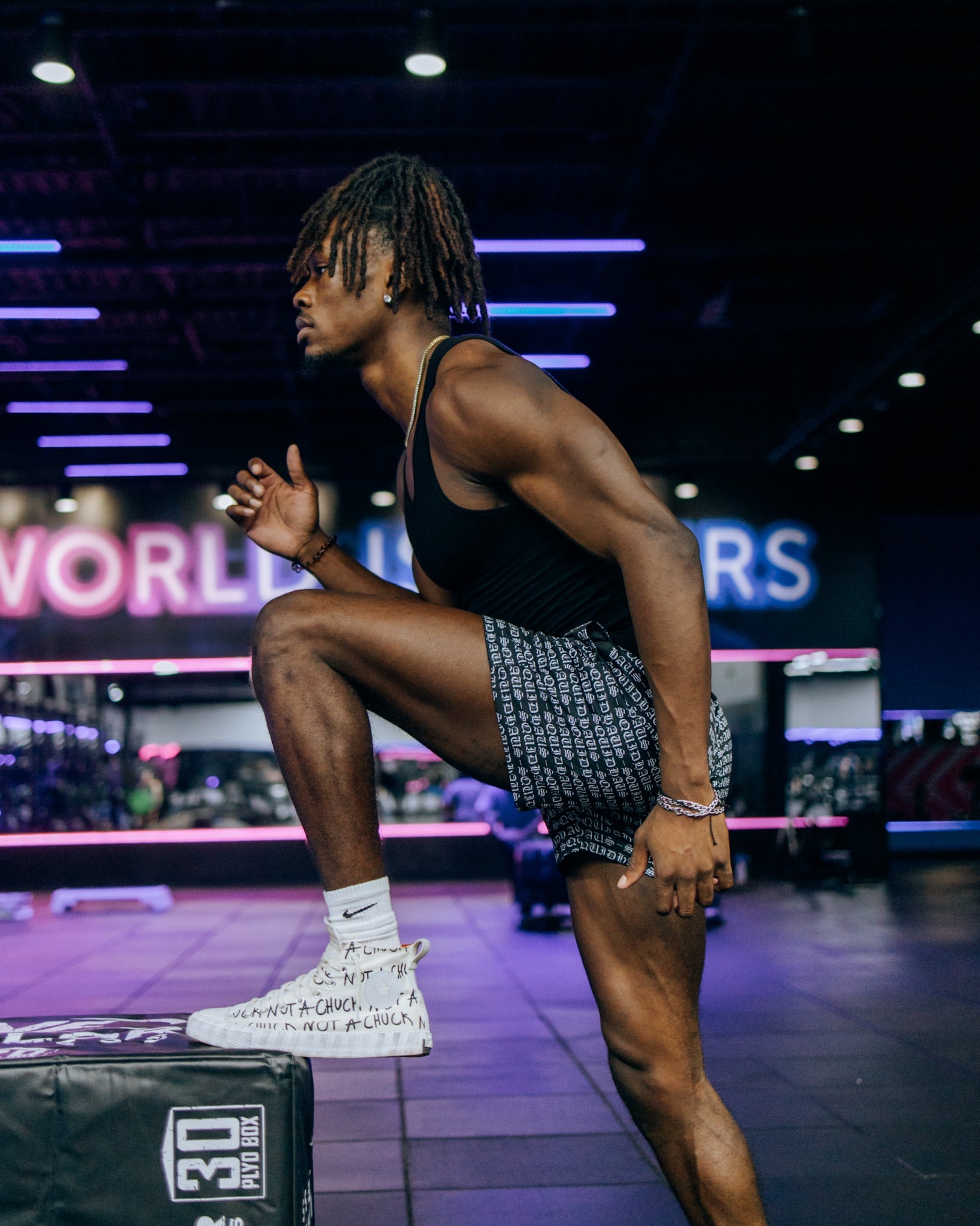 A bodybuilder stretching at the gym wearing 4 in inseam mesh shorts in black, from SquidHaus