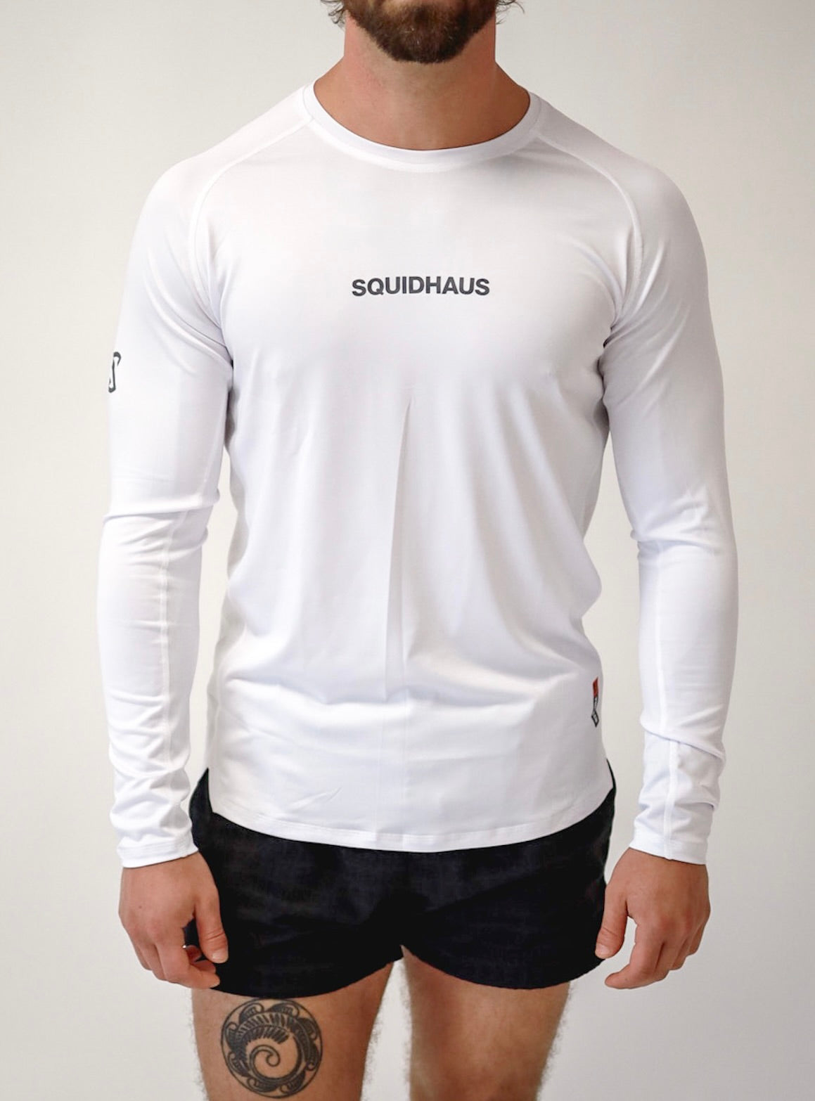 A front view of an athlete wearing a Pro-Tech V1 athletic-fitted long sleeve t-shirt in white and 4" inseam mesh shorts in black, both from SquidHaus