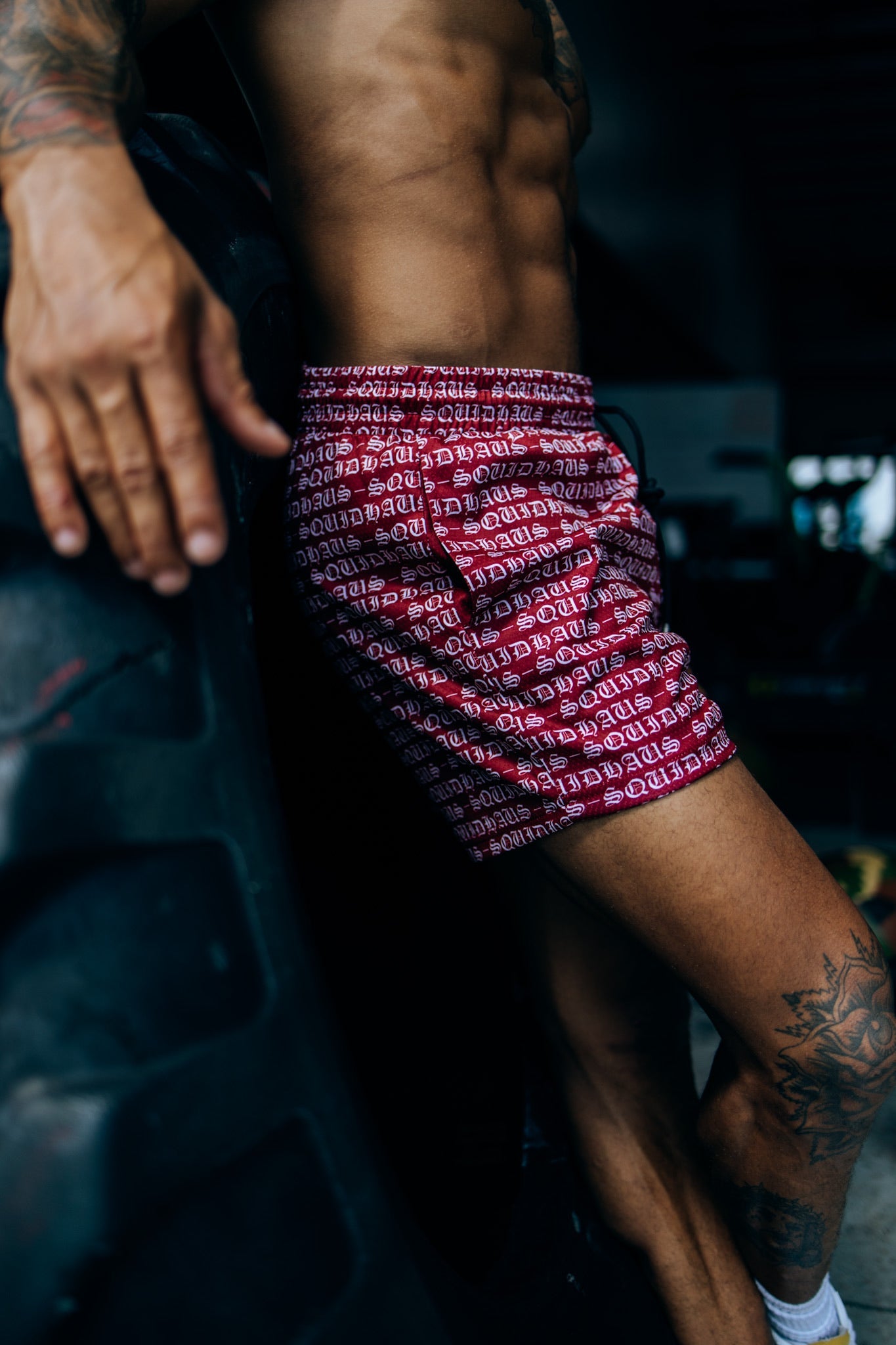 Side view of an athlete wearing 4 inch inseam mesh shorts in red, from SquidHaus