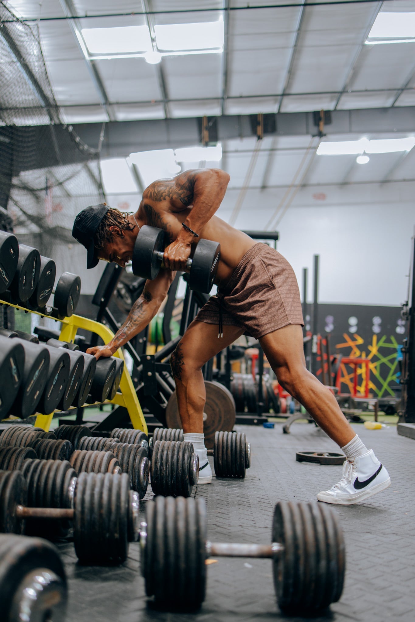 A bodybuilder lifting weights at the gym, wearing SquidHaus' brown 4 inch inseam mesh shorts