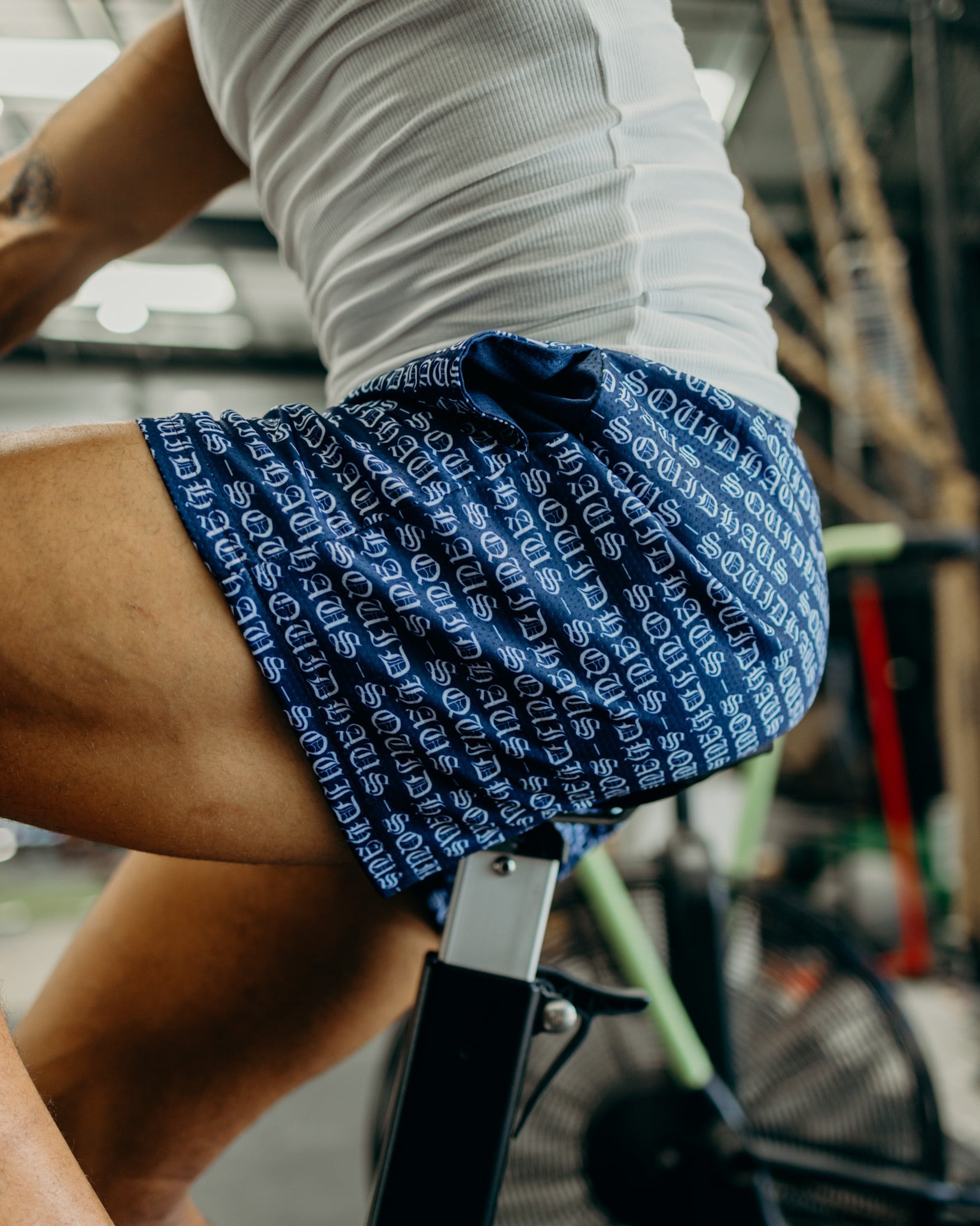 An athletic man on a cycling machine at the gym wearing 4 inch inseam mesh shorts in navy blue, from SquidHaus